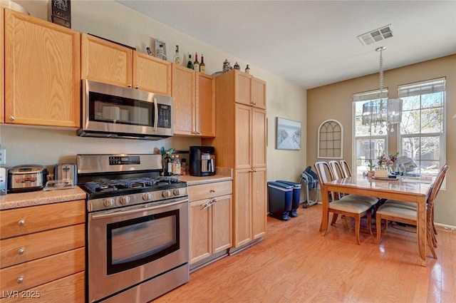 kitchen featuring visible vents, hanging light fixtures, stainless steel appliances, light countertops, and light brown cabinets