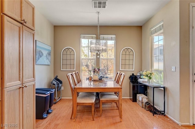 dining space with light wood finished floors, an inviting chandelier, visible vents, and baseboards