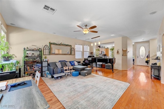 living area with ceiling fan, light wood-type flooring, and visible vents