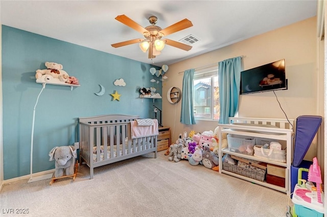 bedroom featuring a nursery area, carpet flooring, ceiling fan, and visible vents