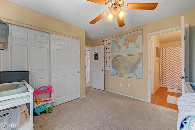 bedroom with a ceiling fan, a closet, light carpet, and baseboards