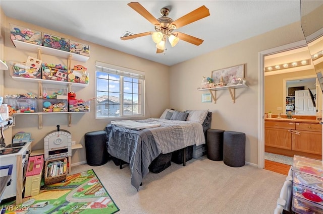 bedroom featuring light carpet, baseboards, a ceiling fan, and ensuite bathroom