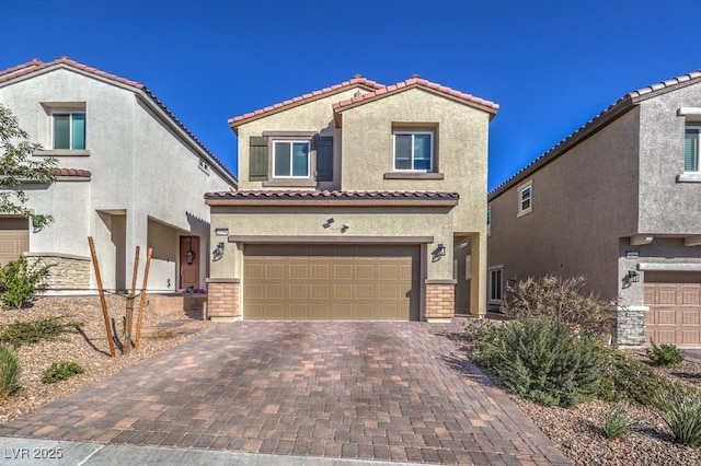 mediterranean / spanish home featuring a garage, decorative driveway, a tile roof, and stucco siding