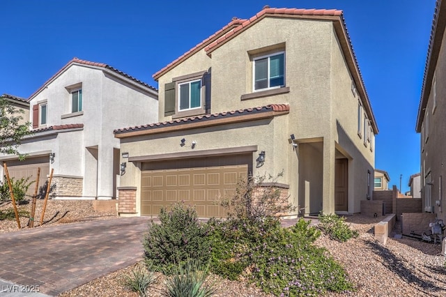 mediterranean / spanish home featuring an attached garage, a tiled roof, decorative driveway, and stucco siding