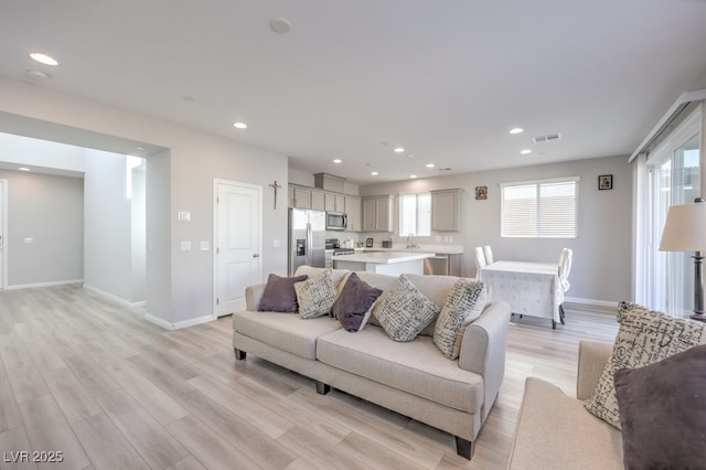 living room with light wood finished floors, visible vents, and recessed lighting