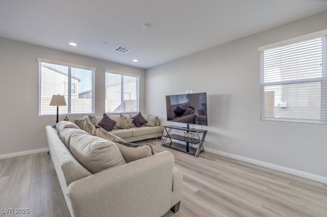 living area featuring light wood-type flooring, visible vents, and baseboards