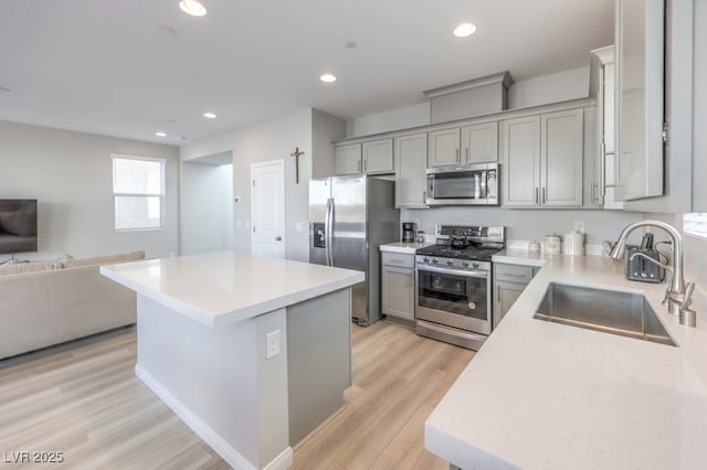 kitchen with a kitchen island, open floor plan, stainless steel appliances, light countertops, and a sink