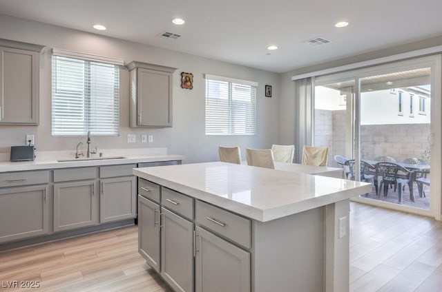 kitchen with a kitchen island, visible vents, a sink, and gray cabinetry