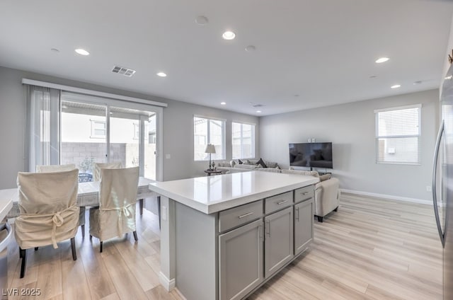 kitchen with light wood finished floors, open floor plan, light countertops, gray cabinetry, and recessed lighting