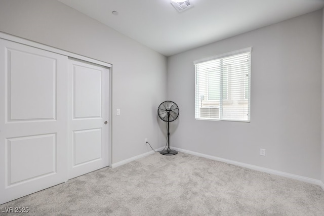 unfurnished bedroom with light carpet, a closet, visible vents, and baseboards