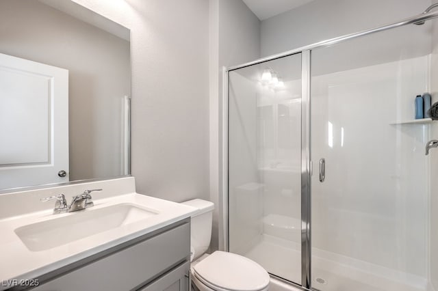 bathroom featuring a shower stall, toilet, and vanity