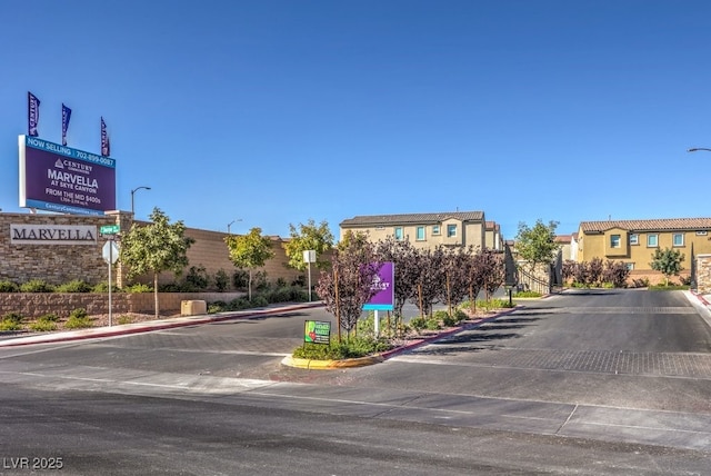 view of street featuring curbs, a gated entry, and street lights