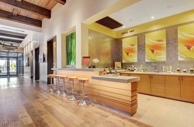 interior space with wooden ceiling, wood finished floors, a sink, backsplash, and beamed ceiling