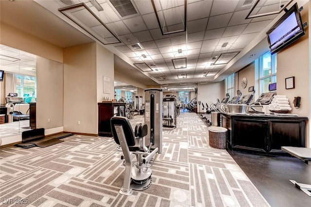 exercise room featuring visible vents, a paneled ceiling, and baseboards