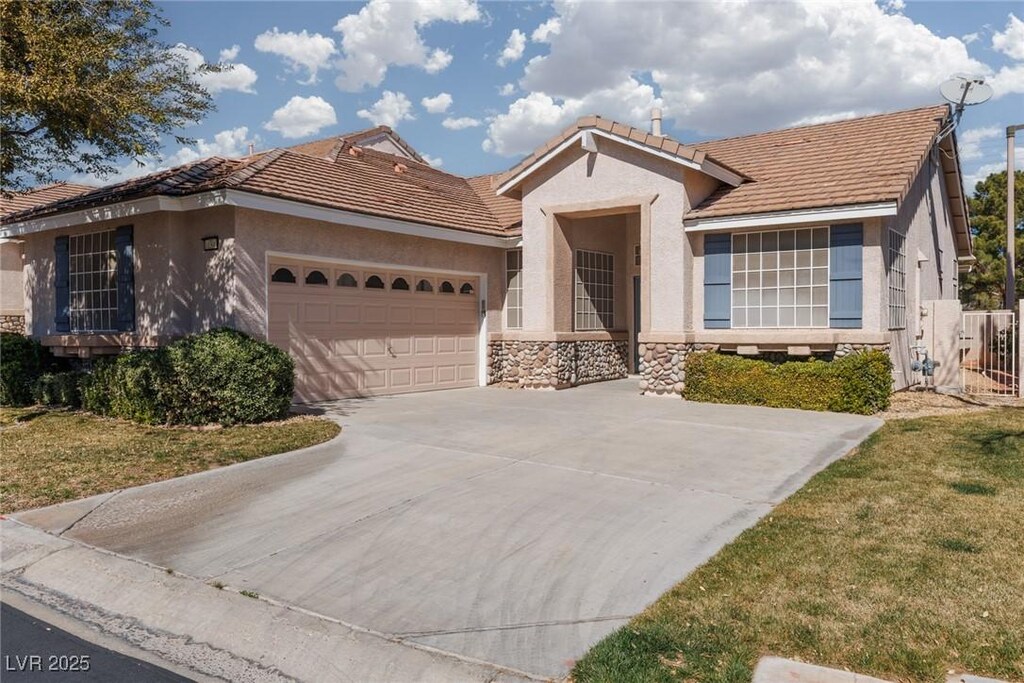10300 Pinto Creek Ln, Las Vegas, NV 89144 - single story home with concrete driveway, stucco siding, a tile roof, stone siding, and a garage
