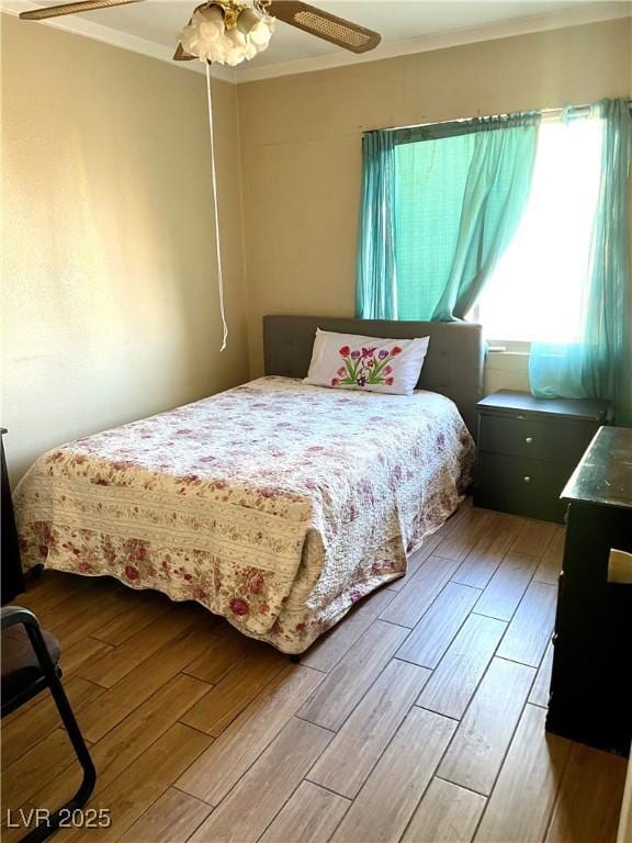 bedroom with ornamental molding, light wood finished floors, and a ceiling fan