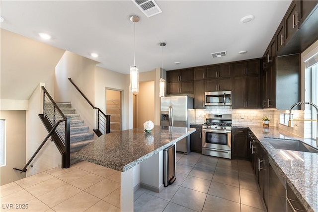 kitchen with dark stone counters, a kitchen breakfast bar, a center island, stainless steel appliances, and a sink