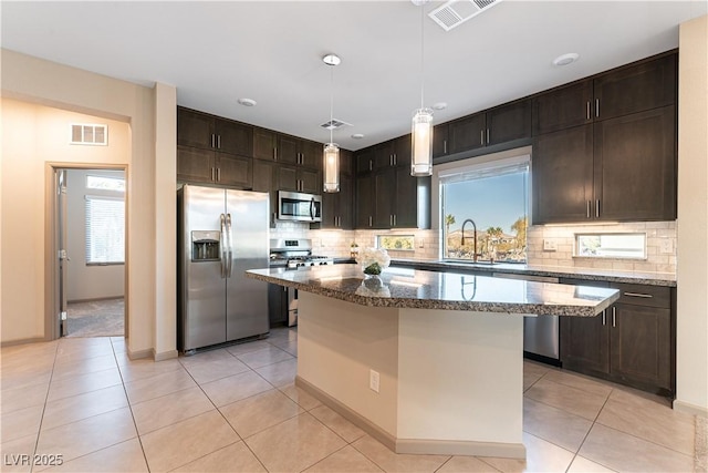 kitchen with a center island, stainless steel appliances, visible vents, hanging light fixtures, and a sink