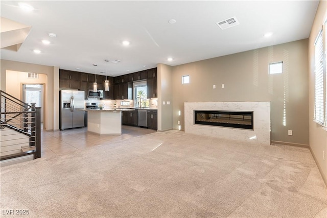 unfurnished living room featuring visible vents, light colored carpet, a premium fireplace, stairway, and recessed lighting