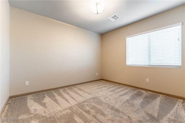 empty room featuring light carpet, visible vents, and baseboards