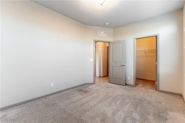 unfurnished bedroom with light colored carpet, visible vents, baseboards, a spacious closet, and a closet