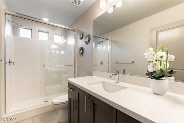 bathroom featuring toilet, vanity, visible vents, tile patterned floors, and a stall shower