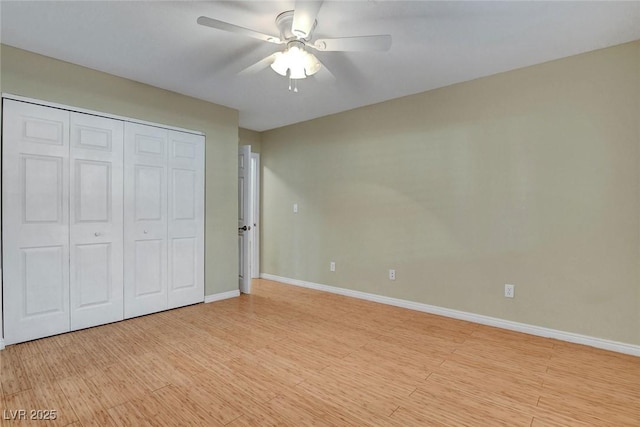 unfurnished bedroom featuring light wood-style flooring, baseboards, ceiling fan, and a closet