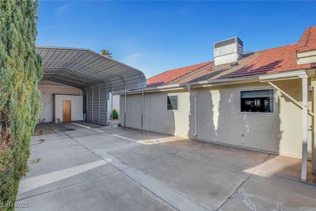 back of house featuring stucco siding, cooling unit, and a detached carport