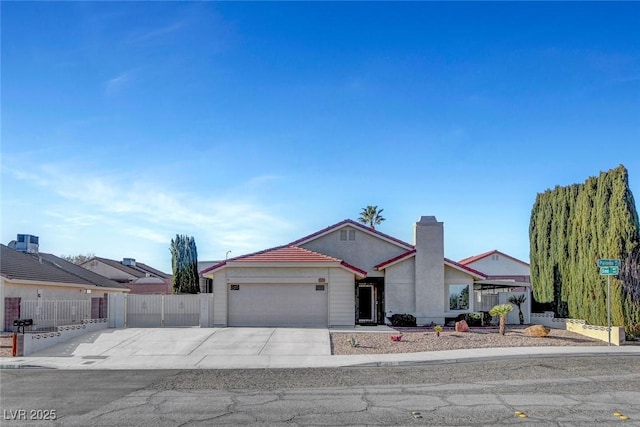 view of front of property featuring an attached garage, a chimney, fence, and concrete driveway