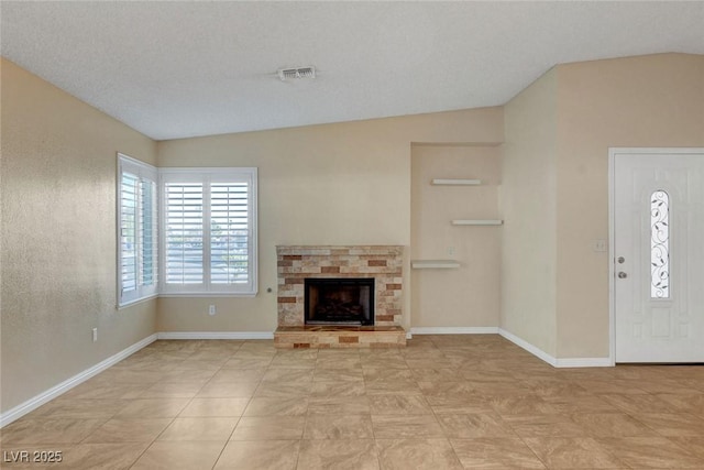 unfurnished living room featuring a fireplace, lofted ceiling, visible vents, a textured ceiling, and baseboards