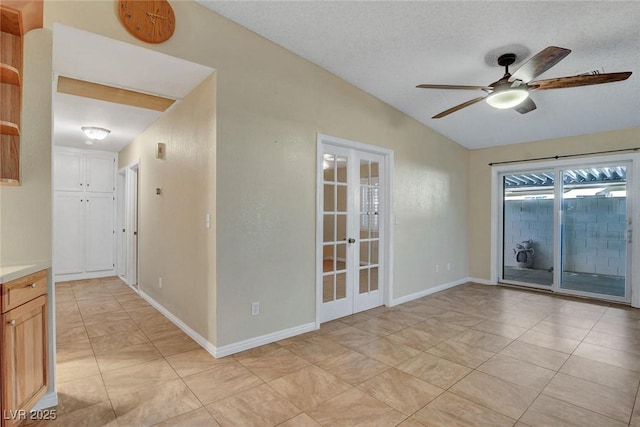 unfurnished room featuring a textured ceiling, a ceiling fan, baseboards, vaulted ceiling, and french doors