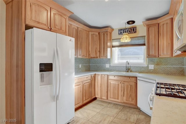 kitchen with light countertops, white appliances, and a sink