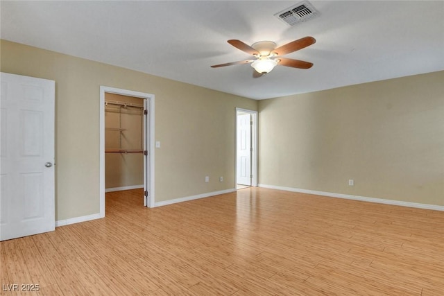 empty room with visible vents, ceiling fan, light wood-style flooring, and baseboards