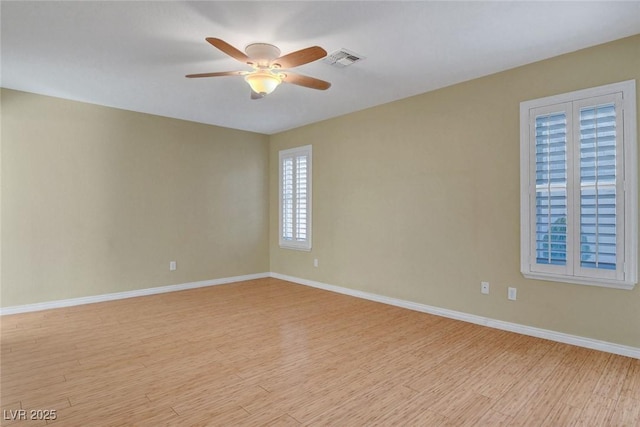 unfurnished room with a ceiling fan, light wood-type flooring, visible vents, and baseboards