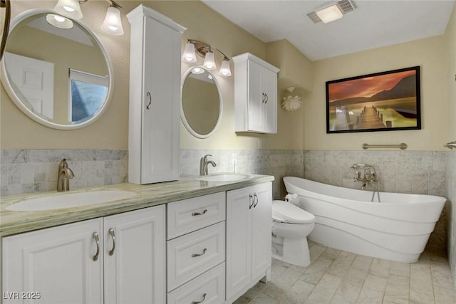 full bathroom featuring toilet, visible vents, a sink, and a freestanding bath