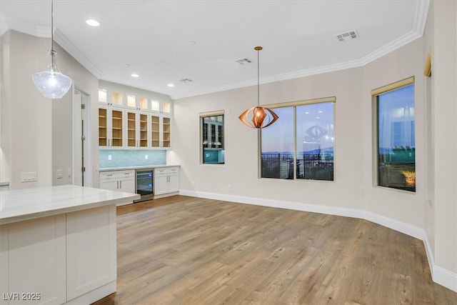 kitchen featuring white cabinets, hanging light fixtures, visible vents, and light stone countertops