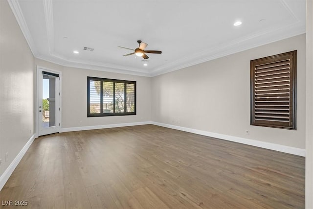 spare room with baseboards, visible vents, ceiling fan, wood finished floors, and crown molding