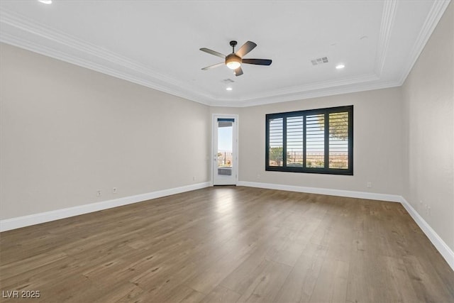 spare room with baseboards, visible vents, a ceiling fan, dark wood-style floors, and ornamental molding