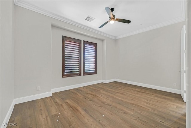 spare room with baseboards, visible vents, wood finished floors, and ornamental molding