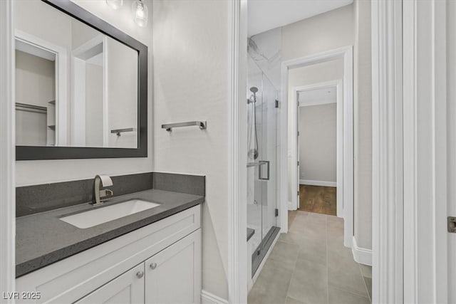 full bathroom featuring a stall shower, tile patterned flooring, baseboards, and vanity