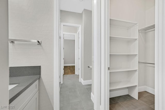 bathroom featuring a spacious closet, baseboards, and vanity