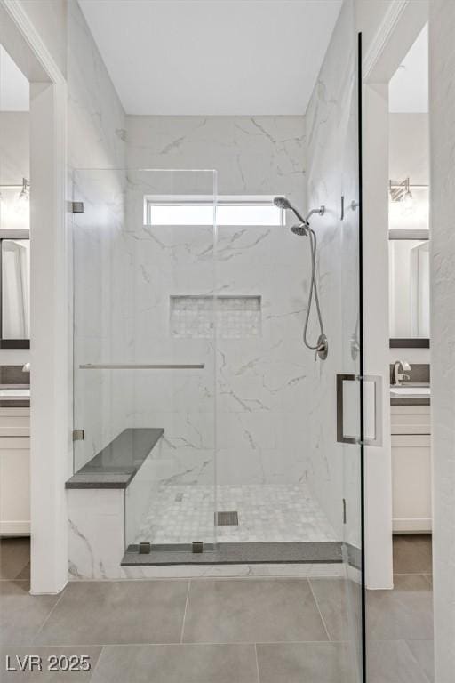 full bath with tile patterned flooring, vanity, and a marble finish shower