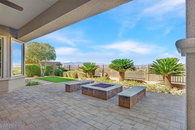 view of patio featuring ceiling fan, an outdoor fire pit, and a fenced backyard