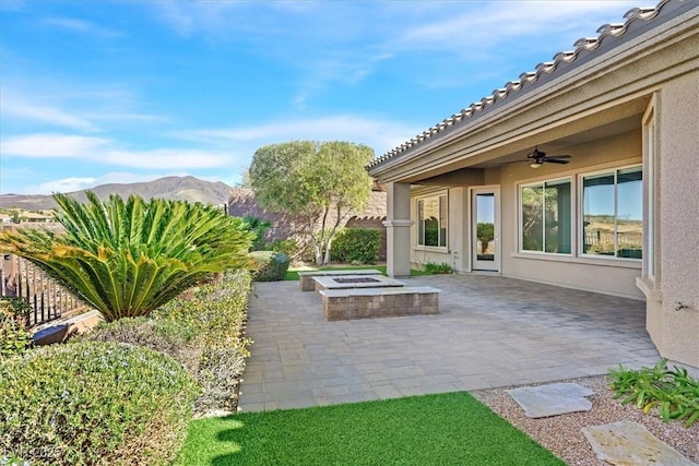 view of patio with ceiling fan, an outdoor fire pit, and a mountain view