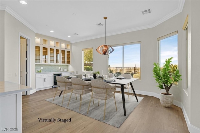 dining room featuring ornamental molding, wine cooler, visible vents, and light wood finished floors