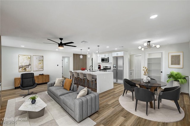 living room featuring baseboards, visible vents, built in features, light wood-type flooring, and recessed lighting