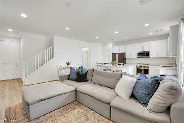 living room featuring light wood-style floors, stairs, visible vents, and recessed lighting