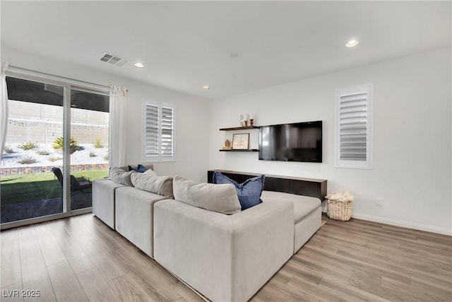 living room with recessed lighting, visible vents, light wood-style flooring, and baseboards