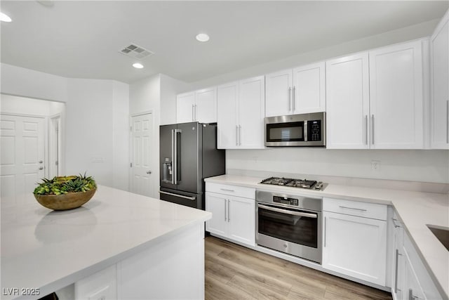 kitchen featuring light wood-type flooring, visible vents, appliances with stainless steel finishes, and white cabinets