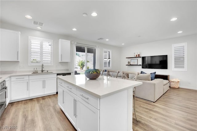 kitchen with visible vents, white cabinetry, light countertops, and a center island